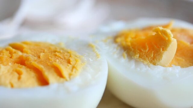 Close up of halved hard boiled egg with bright yellow yolk and white albumen displayed on plate