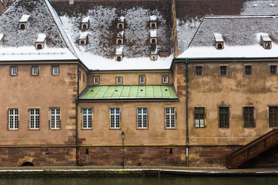 Historic Building Facade Along Canal Covered in Snow in Strasbourg