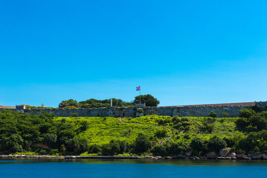 Historic Fortress with Cuban Flag Overlooking Sea in Havana