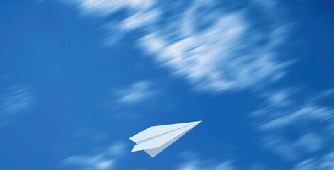 White paper plane soars through vibrant blue sky. Soft clouds drift behind, adding gentle motion. Simplistic design evokes freedom and imagination. Ideal for themes of dreams, childhood, or escape © Issarawat Tattong