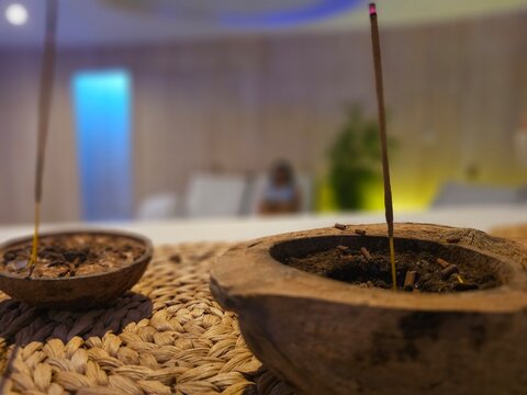 Incense sticks burning in wooden holders on a woven mat in a calm indoor