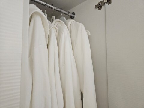 White robes hanging in a closet in a hotel room