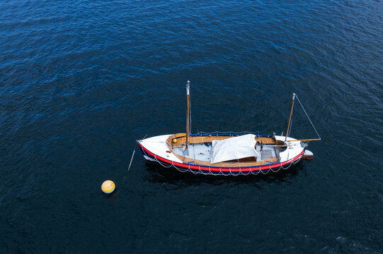 United Kingdom - 26 July 2022: Aerial view of the Herbert John historic lifeboat moored on calm dark water with a yellow buoy nearby.