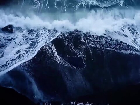 Powerful Ocean Breaker Curling Across Deep Blue Water. Close view of a powerful ocean breaker forming a curling crest before collapsing into white spray and foam, highlighting the energy and motion.