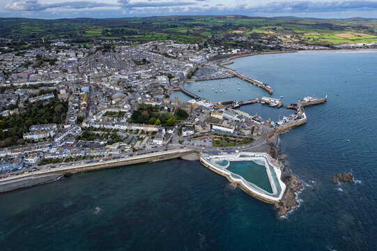 Penzance, United Kingdom - 15 October 2023: Aerial view of Jubilee Pool, a historic art deco lido, situated along the coastline with the town of Penzance, harbor, and surrounding green fields.