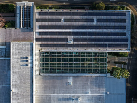 Wantirna South, Australia - 03 September 2026: Aerial view of a commercial building roof with extensive solar panel arrays and a glass atrium, surrounded by paved areas and greenery.