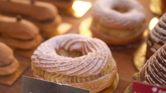 Close-up cinematic footage of various french pastries beautifully displayed in a bakery shop window, delicious treats in motion