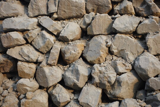 Stacked boulder retaining wall structure built on a steep slope at a quarry mining site.