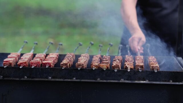 Man grilling shashlik skewers with meat on brazier. Barbecue cooking meat kebab on grill with smoke. Outdoor barbecue party food preparation concept