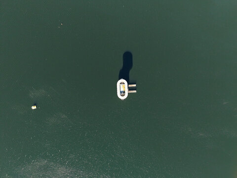 Silvan, Victoria, Australia - 01 September 2026: Aerial view of the intake tower at Silvan Reservoir surrounded by deep green water with a long shadow cast on the surface.
