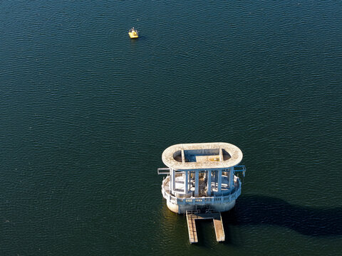 Silvan, Victoria, Australia - 01 September 2026: Aerial view of the Silvan Reservoir Park intake tower rising from the dark reservoir water with a small yellow buoy nearby.