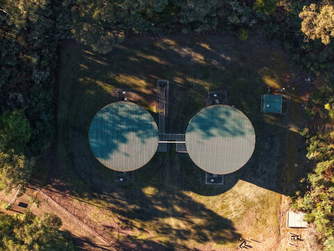 Silvan, Australia - 01 September 2026: Aerial view of Silvan Reservoir Park featuring two large circular water tanks surrounded by dense forest and native vegetation.