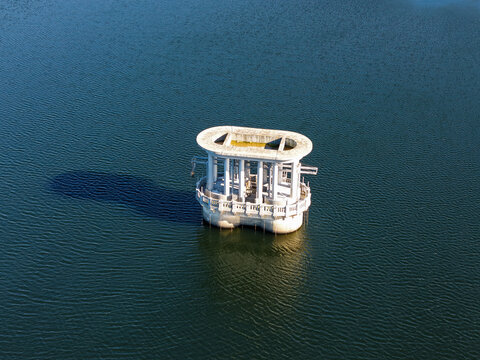 Silvan, Victoria, Australia - 01 September 2026: Aerial view of the historic concrete valve tower of Silvan Reservoir rising from the deep blue water, casting a long shadow.
