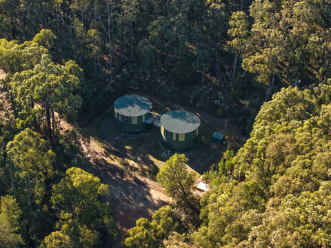 Silvan, Victoria, Australia - 01 September 2026: Aerial view of Silvan Reservoir Park featuring two large green water storage tanks nestled within a dense eucalyptus forest.