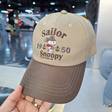 hand holding beige and brown two tone GQ baseball cap with embroidered sailor snoopy character peanuts logo on August 24, 2026 in Bangkok, Thailand.