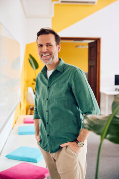 Cheerful businessman stands confidently in a modern office