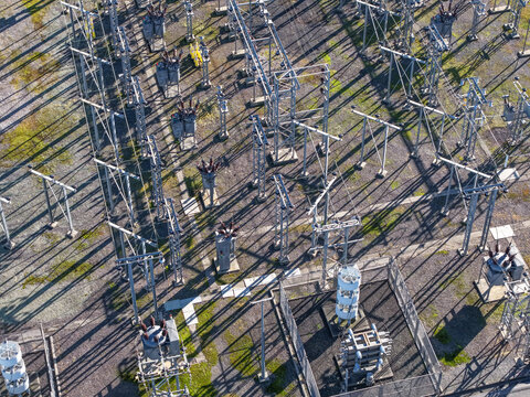 Bayswater North, Australia - 29 August 2026: Aerial view of Bayswater Zone Substation with electrical transformers, steel pylons, and power lines casting long shadows on gravel.
