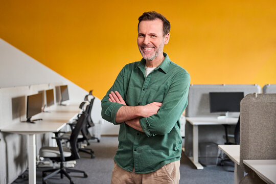 Smiling businessman crosses arms in an open space office