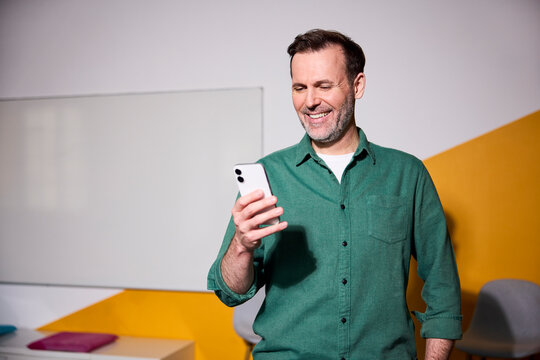 Smiling businessman using smartphone in modern office