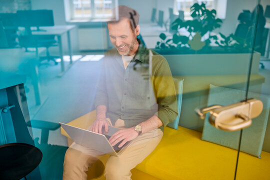 Relaxed businessman using laptop in modern office pod