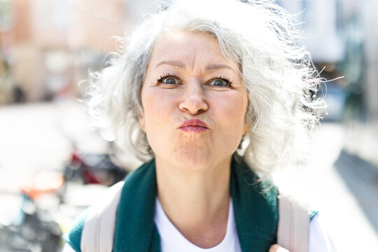 A woman makes a playful face outdoors in the city