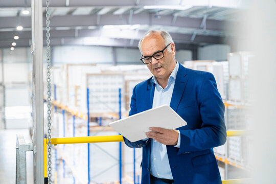 A businessman checks logistics on a tablet in a warehouse