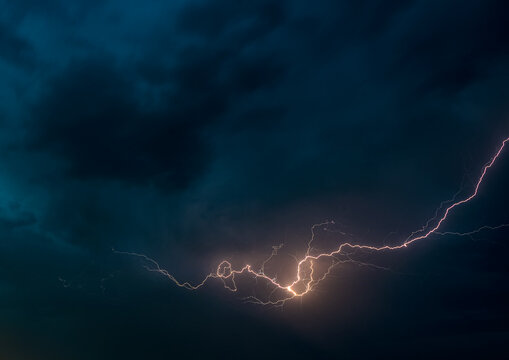 View of a bright lightning bolt striking across a dark, stormy night sky over Multan, Punjab, Pakistan.