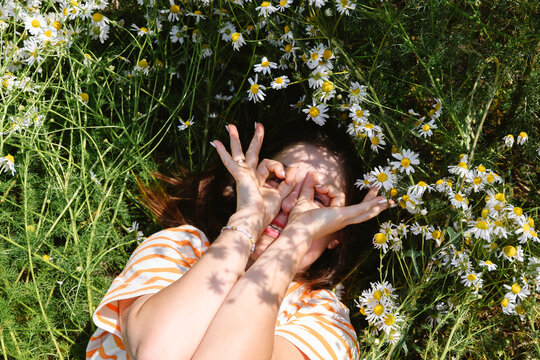 Playful woman makes hand glasses in a summer flower field