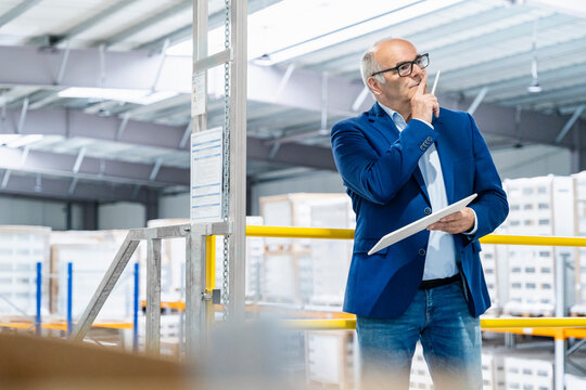 Male supervisor holds a tablet and plans logistics in a warehouse