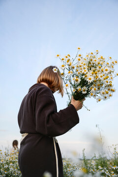 Woman holding a chamomile bouquet in a summer field with a girl