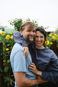A smiling man and woman hug each other in a summer garden