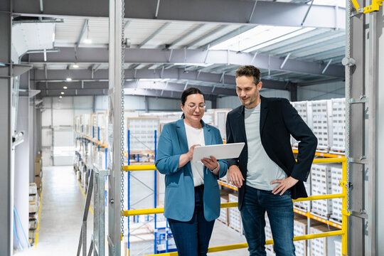 Businesswoman and businessman use tablet in warehouse