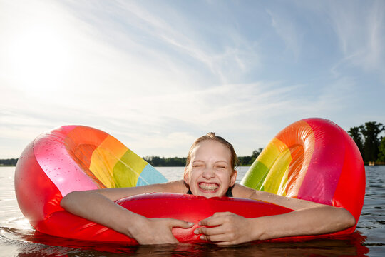 Happy girl holds a rainbow inflatable in the summer lake