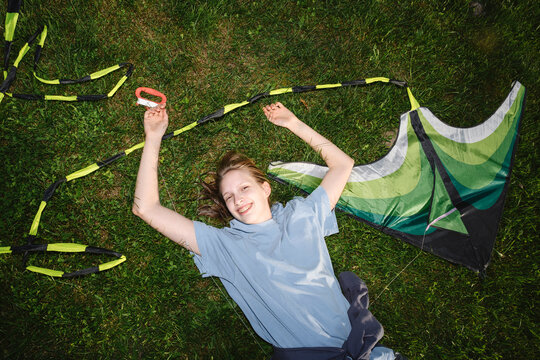 Smiling girl holds a kite on green grass during summer