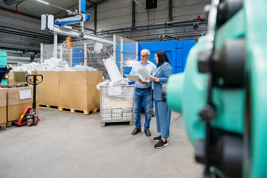 A man and a woman review tablet data in a production hall
