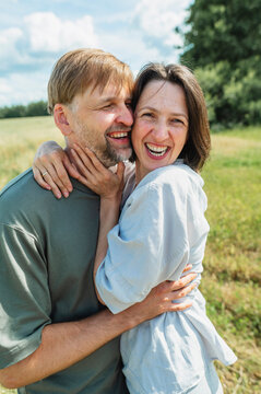 A happy man and woman hug each other outdoors in a summer field
