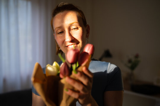 Smiling woman holds a beautiful tulip bouquet at home
