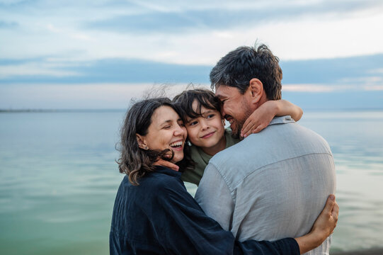 A happy family hugs their son by the sea during summer vacation