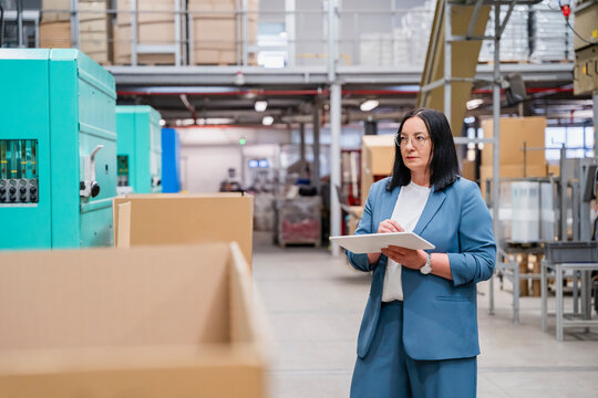 A businesswoman inspects a production hall using a tablet