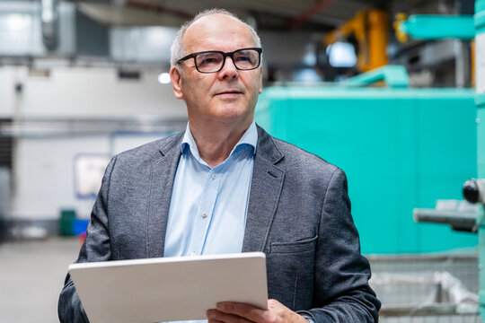 Male manager holds a tablet inside a production hall