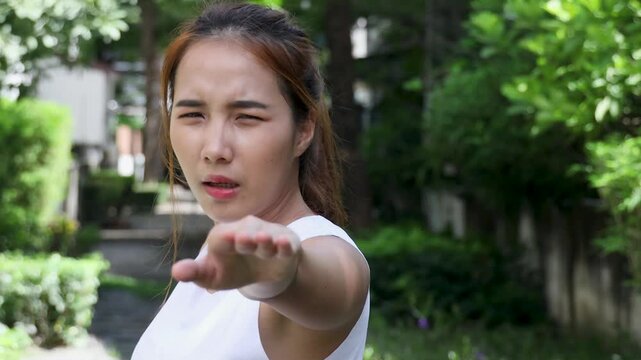 asian woman in warrior pose shaking and wobbling in a sunny park, effort and concentration on her face