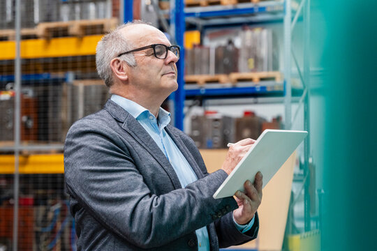 Male manager checks inventory with a tablet in a production hall