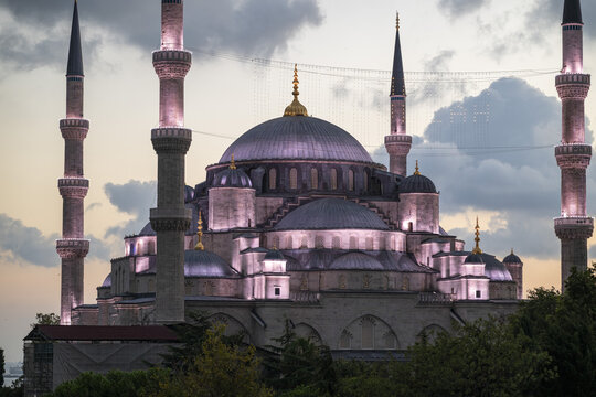 View of the Blue Mosque with its iconic domes and minarets illuminated against a soft sunset sky in Istanbul, Istanbul, Turkiye.