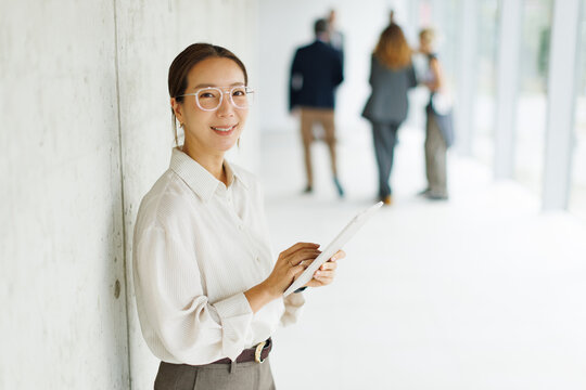 Smiling businesswoman holds a tablet in an office hallway