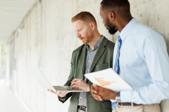 A businessman and a colleague analyze a laptop in a modern office