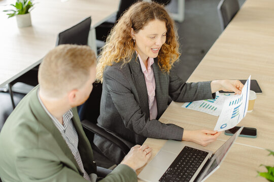 Businesswoman and businessman analyze a chart at the office