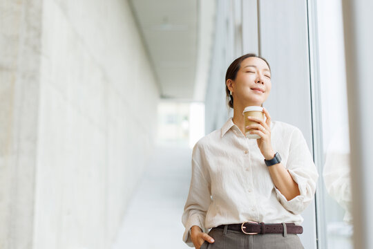 Relaxed businesswoman enjoying a coffee break by the office window