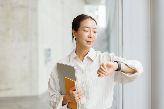 Businesswoman checks her smartwatch holding a laptop in the office