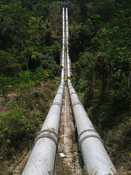 View of the massive steel inverted siphon pipelines of the Talangagung Metro Syphon transporting irrigation water across the valley and terrain slopes in Malang, East Java, Indonesia.