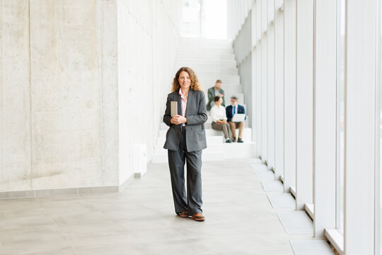 Confident businesswoman stands in a modern office with her team